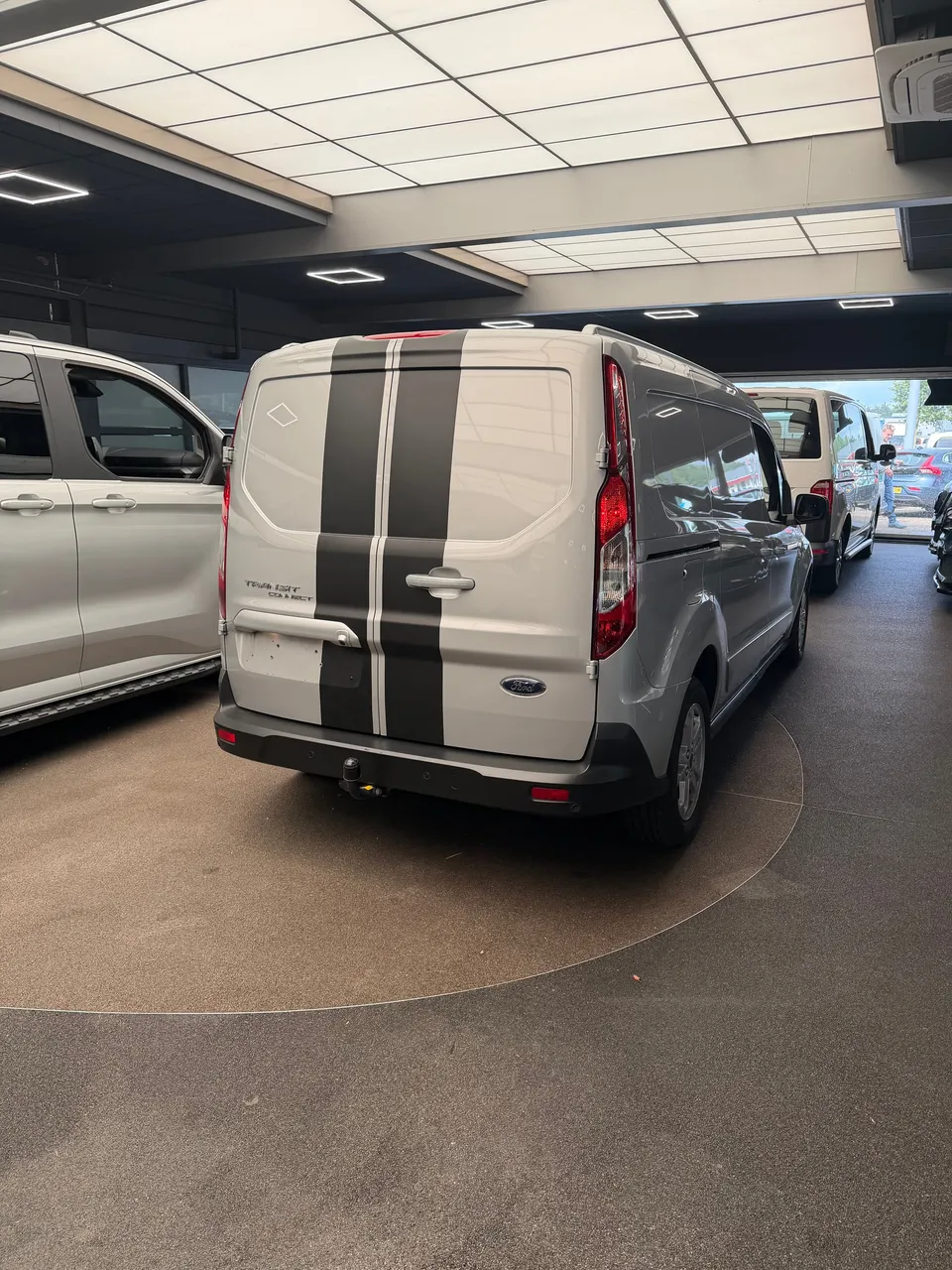 Zilvergrijze Ford bestelwagen van achteren met zwarte striping