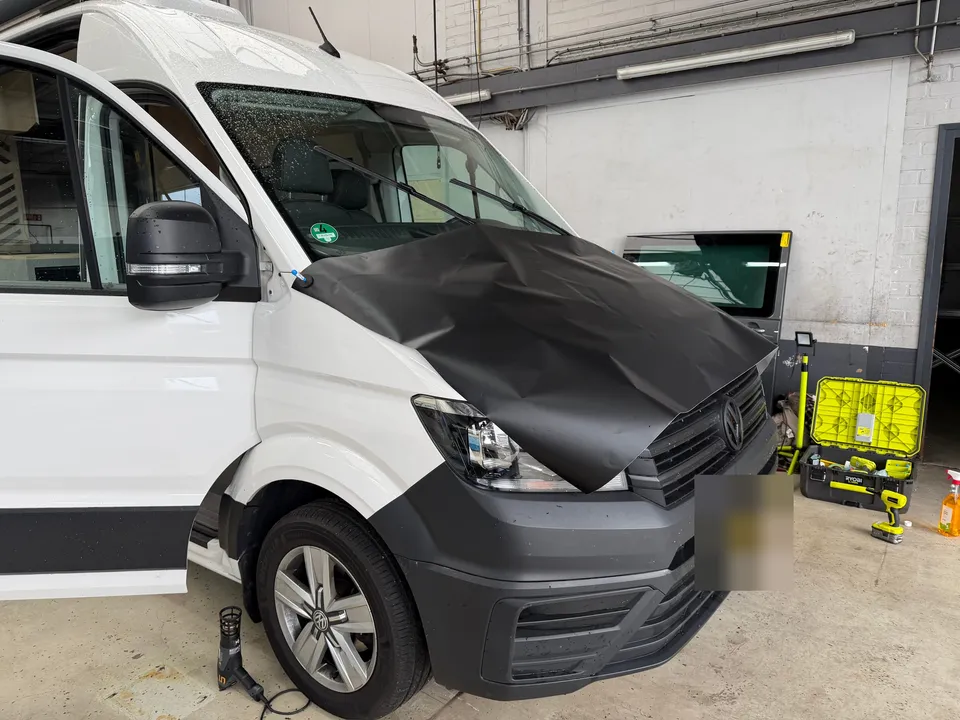 Camper tijdens het wrappen: zwarte folie over de motorkap