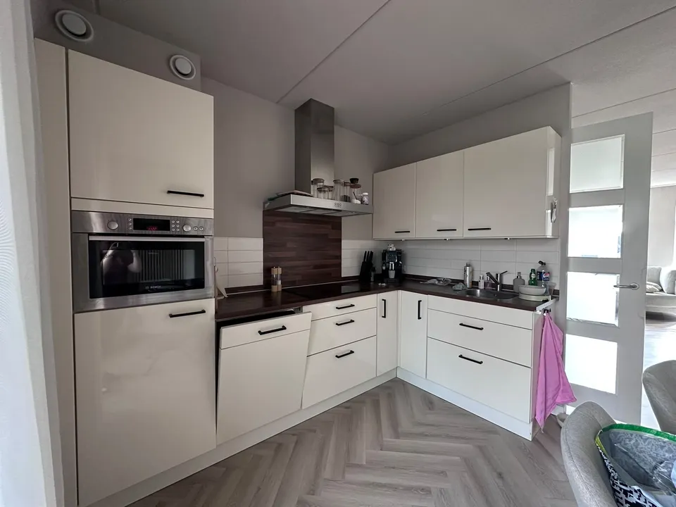 Keuken vóór het wrappen: crèmekleurige keuken met donker werkblad