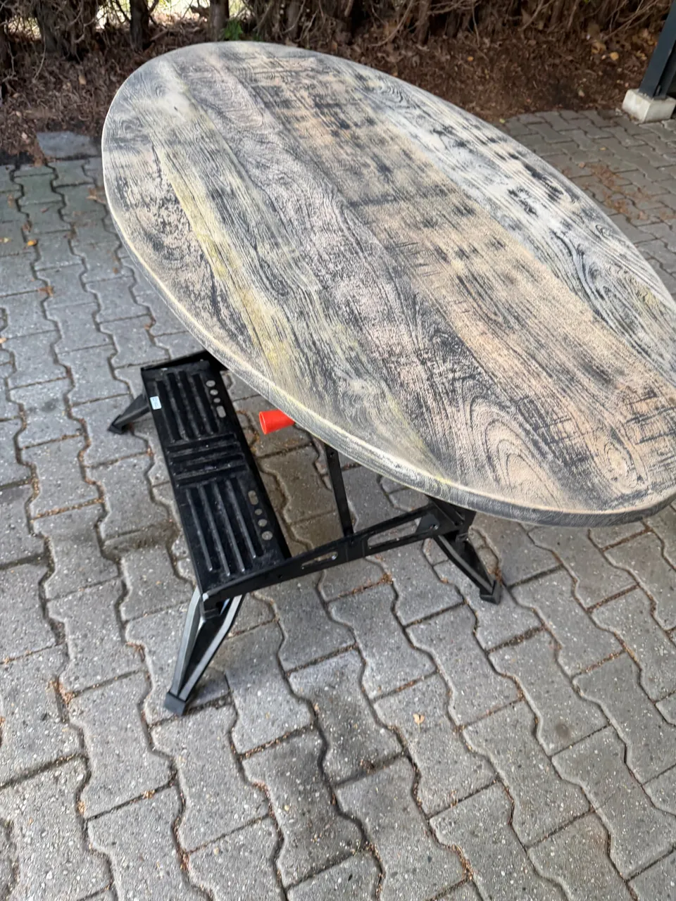 Ovale tafel met verweerd houten blad op een werkbank buiten